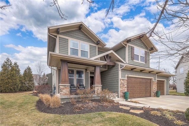 craftsman house featuring a porch, an attached garage, a front yard, stone siding, and driveway