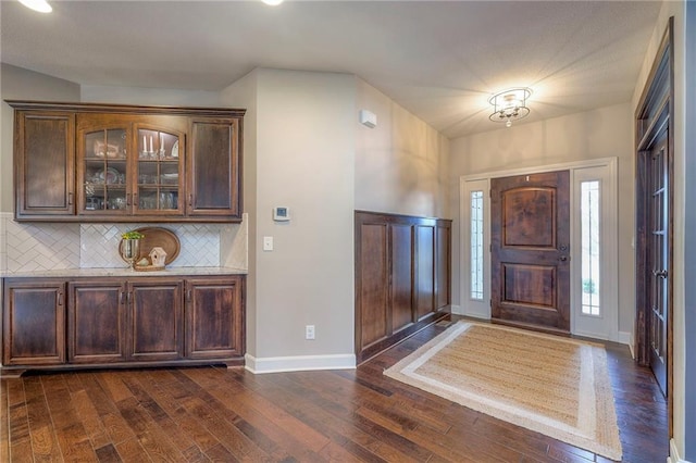 foyer with dark wood-style flooring and baseboards