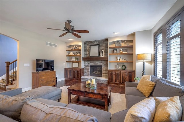 living room with a fireplace, wood finished floors, visible vents, built in features, and stairs