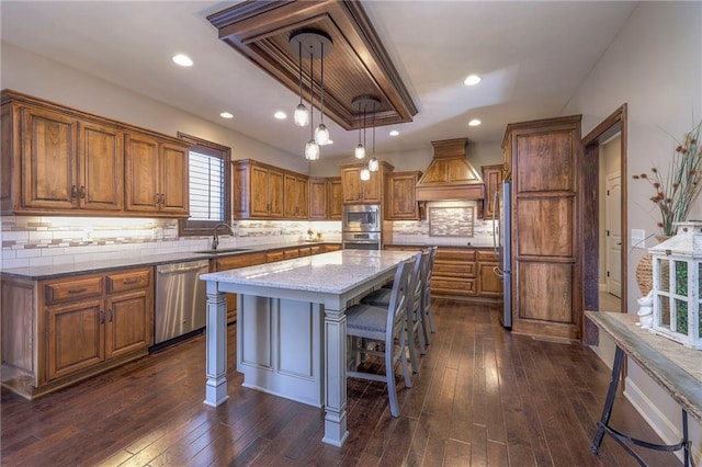 kitchen with a kitchen island, appliances with stainless steel finishes, brown cabinets, a kitchen breakfast bar, and a sink