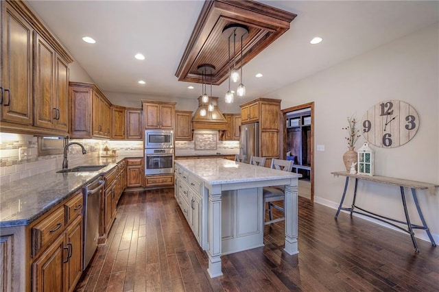 kitchen featuring dark wood-style floors, a breakfast bar area, appliances with stainless steel finishes, brown cabinets, and a sink