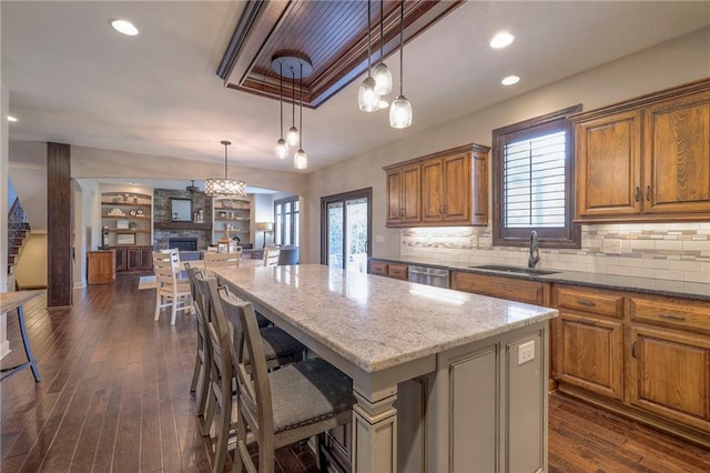 kitchen with a center island, brown cabinetry, dark wood-type flooring, open floor plan, and a sink