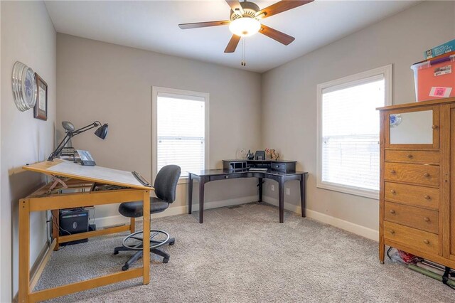 carpeted office space with a ceiling fan and baseboards