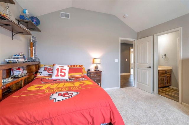 bedroom with lofted ceiling, ensuite bathroom, carpet flooring, visible vents, and baseboards