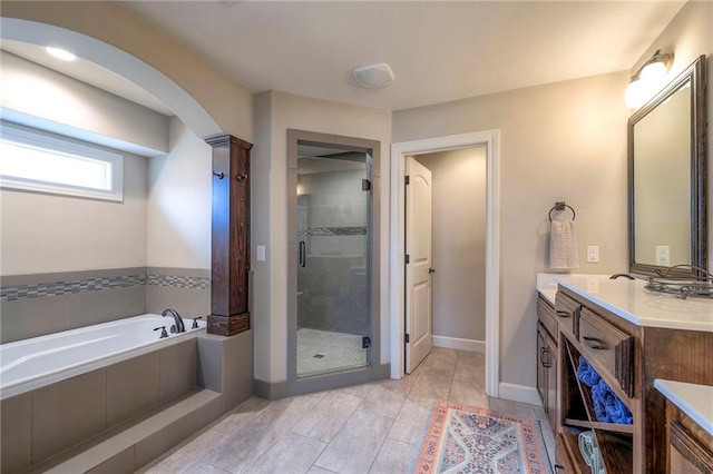 bathroom with a stall shower, baseboards, a garden tub, and vanity