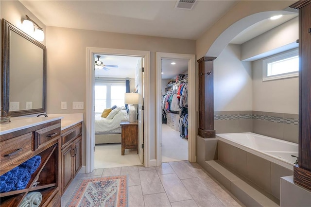 ensuite bathroom with visible vents, a spacious closet, vanity, ensuite bath, and a bath