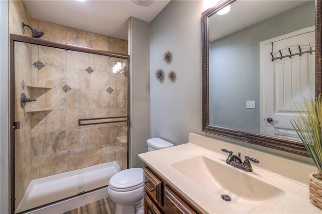 bathroom featuring a shower stall, toilet, and vanity