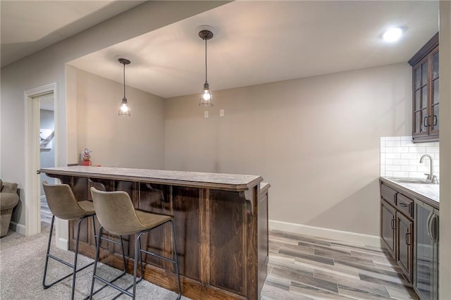 bar with baseboards, decorative backsplash, indoor wet bar, and a sink