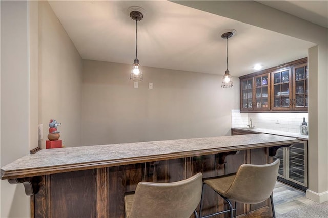 bar featuring wine cooler, backsplash, hanging light fixtures, wet bar, and a sink