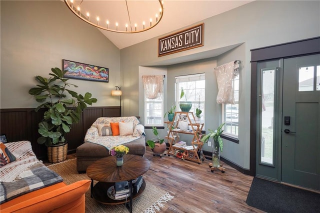 foyer entrance with high vaulted ceiling, an inviting chandelier, and wood finished floors