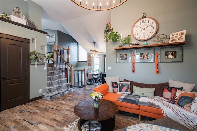 living room with a chandelier, lofted ceiling, wood finished floors, and stairs