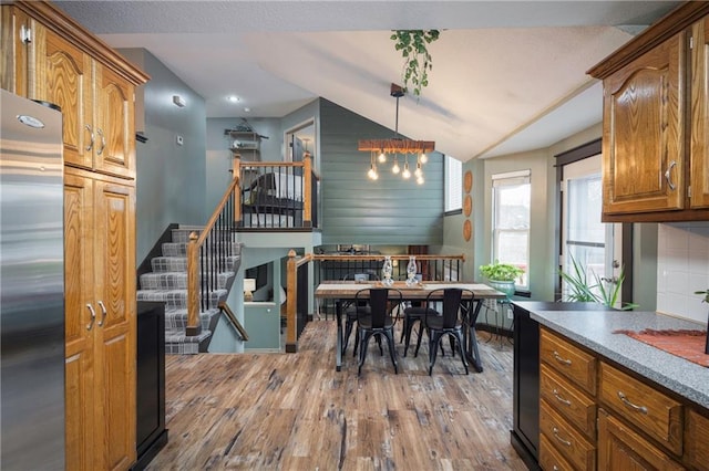 dining room with vaulted ceiling, stairway, wood finished floors, and a textured ceiling