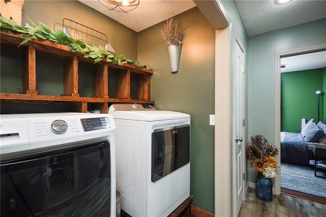 clothes washing area with wood finished floors, baseboards, laundry area, a textured ceiling, and independent washer and dryer