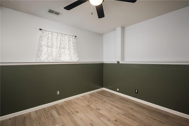 spare room with visible vents, baseboards, ceiling fan, wood finished floors, and a textured ceiling