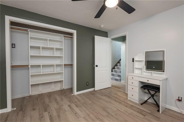 unfurnished office featuring light wood finished floors, baseboards, a textured ceiling, and a ceiling fan