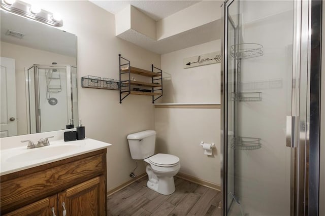 bathroom featuring vanity, wood finished floors, baseboards, a shower stall, and toilet