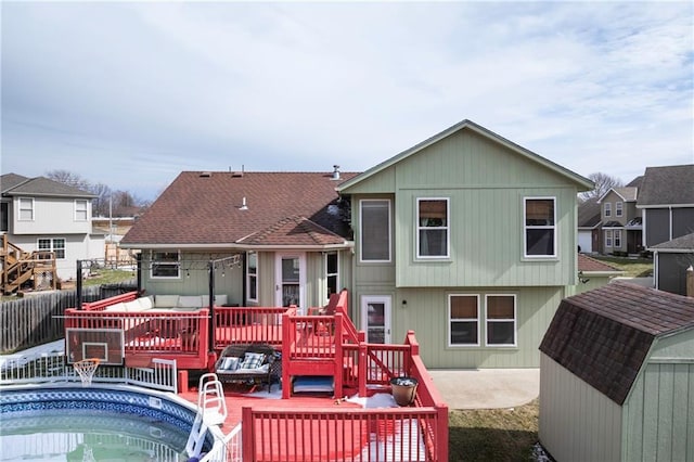 back of house with fence, a storage shed, a deck, an outbuilding, and a jacuzzi