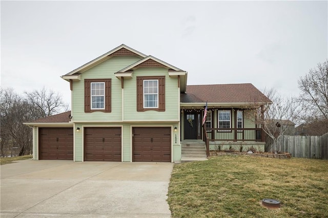 tri-level home featuring fence, covered porch, concrete driveway, a front lawn, and a garage