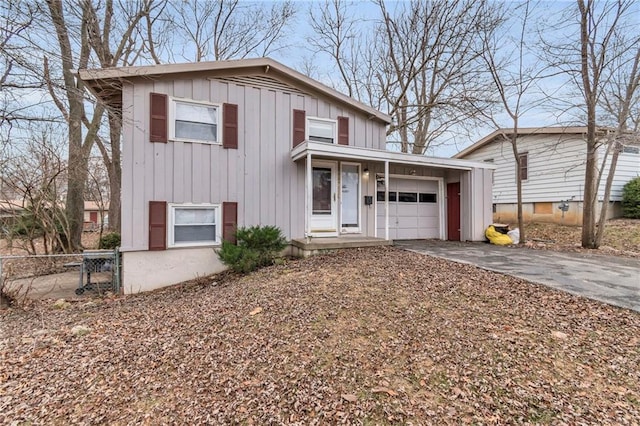 split level home with board and batten siding, fence, an attached garage, and aphalt driveway