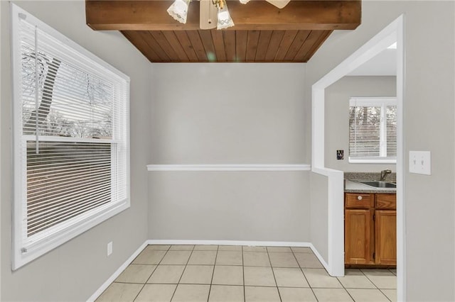 unfurnished dining area with ceiling fan, light tile patterned flooring, a sink, wood ceiling, and beam ceiling