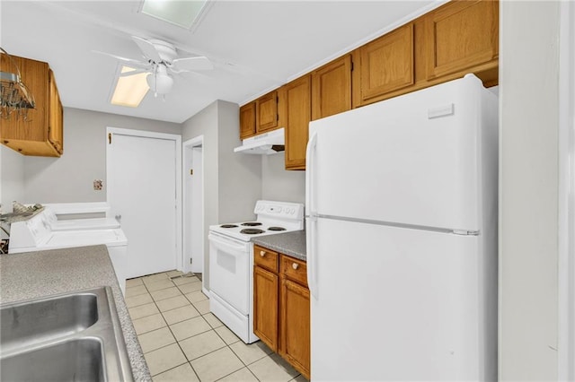 kitchen featuring white appliances, light tile patterned floors, brown cabinets, under cabinet range hood, and a sink