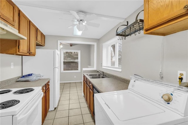 kitchen featuring light tile patterned floors, brown cabinetry, washer / clothes dryer, under cabinet range hood, and a sink