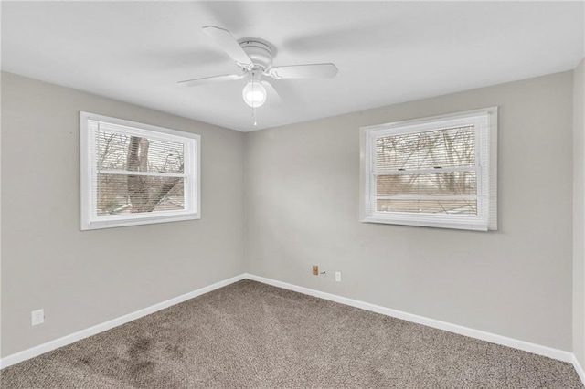 unfurnished room featuring a wealth of natural light, carpet, ceiling fan, and baseboards