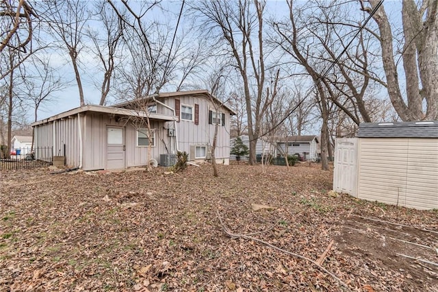 view of side of property with board and batten siding, an outbuilding, a storage unit, fence, and central AC