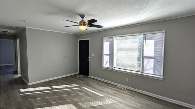 unfurnished room with visible vents, baseboards, ornamental molding, wood finished floors, and a textured ceiling