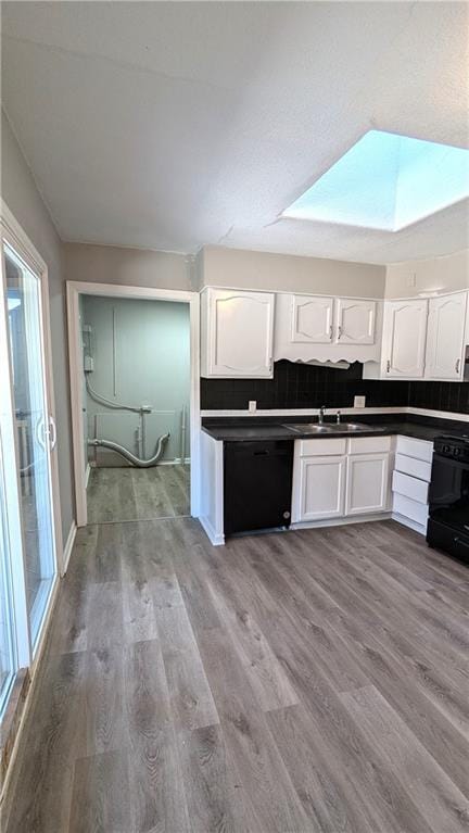 kitchen featuring stove, dark countertops, wood finished floors, and white cabinetry