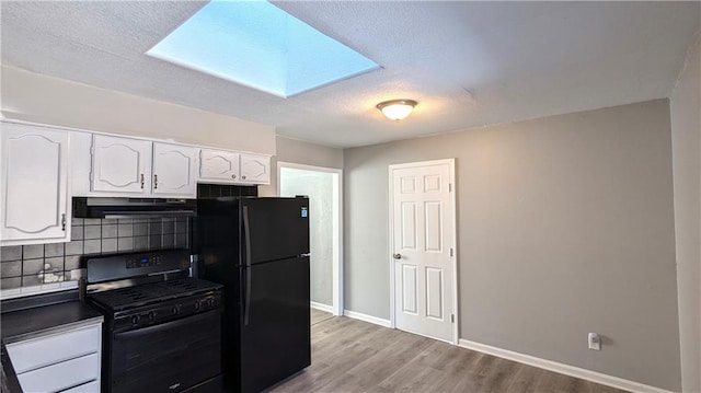 kitchen featuring light wood-style flooring, decorative backsplash, white cabinetry, under cabinet range hood, and black appliances