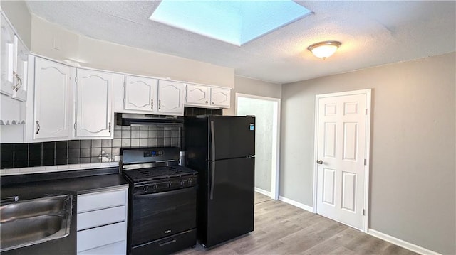 kitchen with white cabinetry, a sink, under cabinet range hood, and black appliances