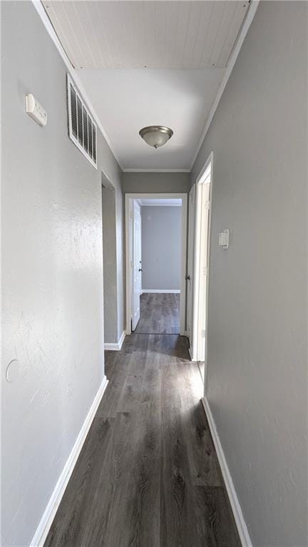 hall with baseboards, crown molding, visible vents, and wood finished floors