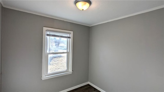 empty room featuring dark wood-style floors, baseboards, and crown molding