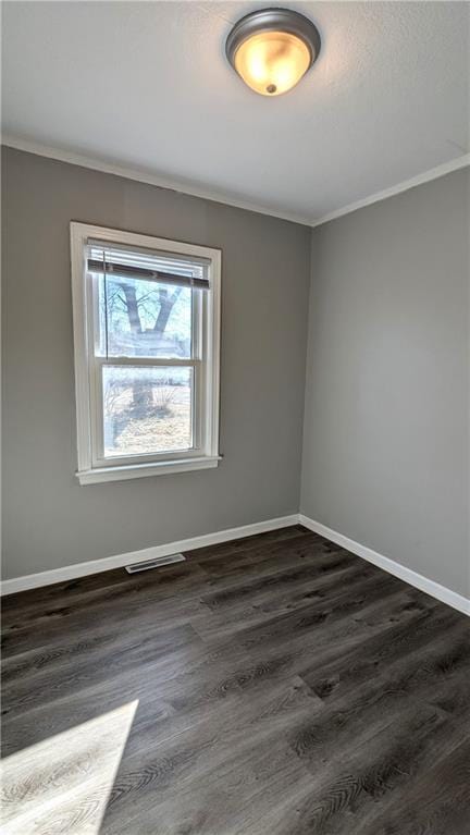 spare room with visible vents, dark wood finished floors, and crown molding