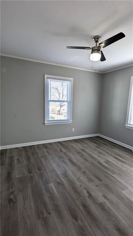 spare room with baseboards, a ceiling fan, dark wood-style flooring, a textured ceiling, and crown molding