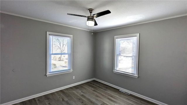 empty room featuring dark wood-style flooring, plenty of natural light, visible vents, and baseboards