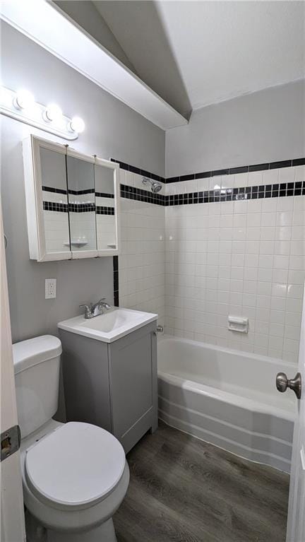 bathroom with lofted ceiling, toilet, tub / shower combination, vanity, and wood finished floors