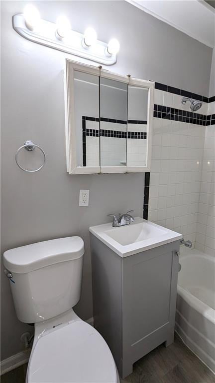 bathroom with shower / bathing tub combination, vanity, toilet, and wood finished floors