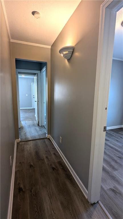 hall with baseboards, ornamental molding, and dark wood-style flooring