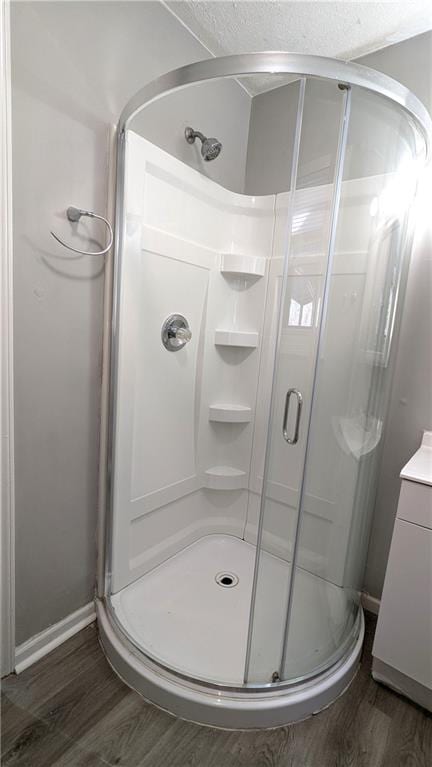 full bath with baseboards, wood finished floors, vanity, and a shower stall