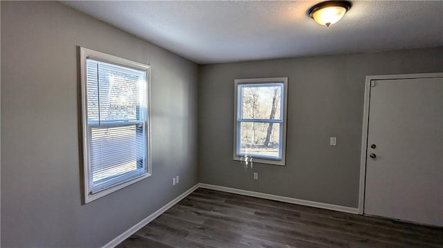 unfurnished room featuring dark wood-style floors, baseboards, and a textured ceiling