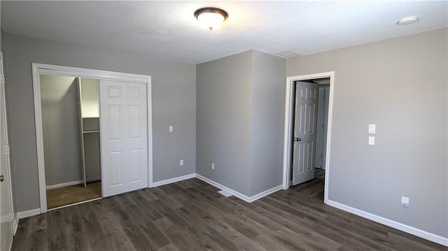 unfurnished bedroom featuring dark wood-type flooring, a closet, and baseboards