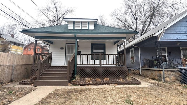 bungalow-style house featuring a porch, roof with shingles, and fence