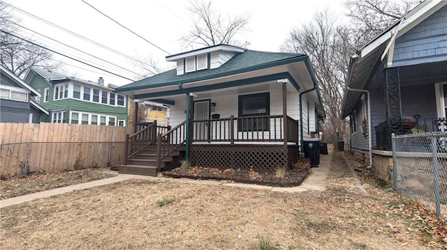 bungalow featuring a shingled roof, fence, and a porch