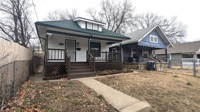 bungalow-style home with a fenced backyard, a porch, and roof with shingles