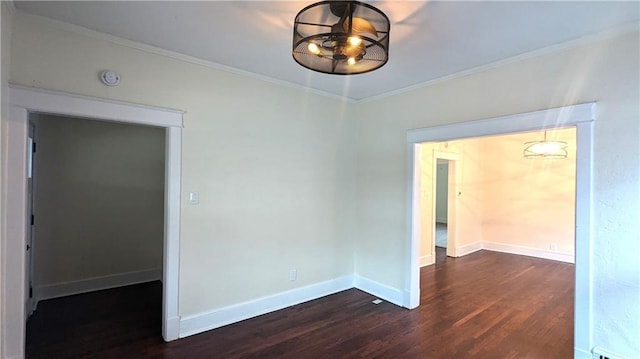 spare room featuring baseboards, wood finished floors, and crown molding