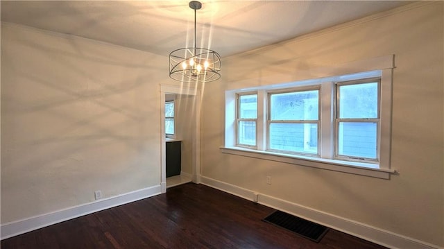 unfurnished dining area with a notable chandelier, crown molding, visible vents, dark wood-type flooring, and baseboards