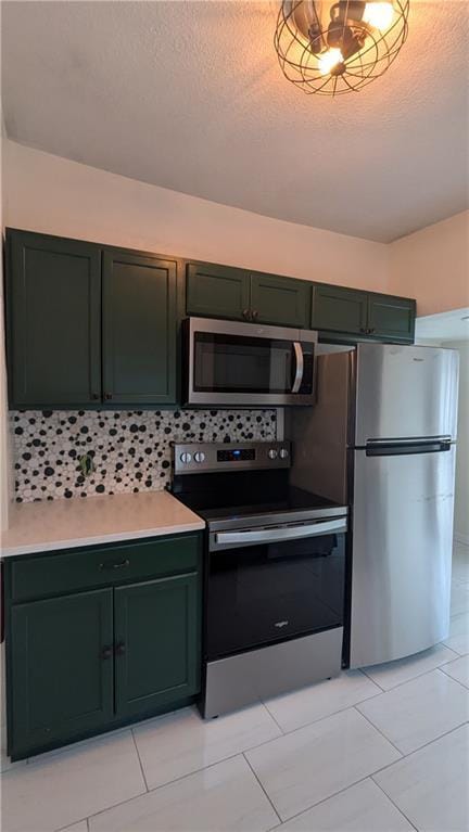 kitchen featuring tasteful backsplash, appliances with stainless steel finishes, light countertops, a textured ceiling, and green cabinetry