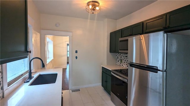 kitchen featuring baseboards, visible vents, stainless steel appliances, light countertops, and a sink